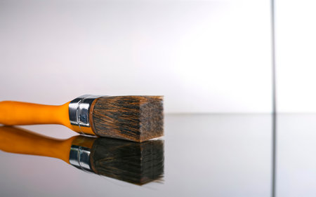 Large clean new paint brush or wallpapering brush with a plastic handle lying on a reflective white surface in a DIYの素材