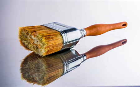 Large clean new paint brush or wallpapering brush with a plastic handle lying on a reflective white surface in a DIYの素材