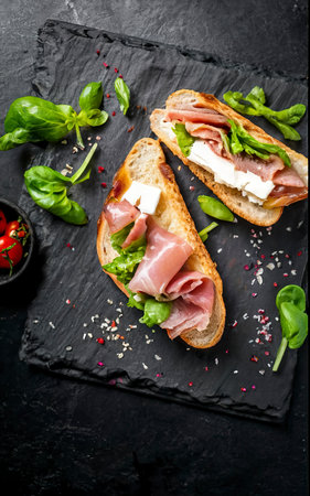 Grilled panini with Prosciutto ham, salad and cheese. Black backgroundの素材