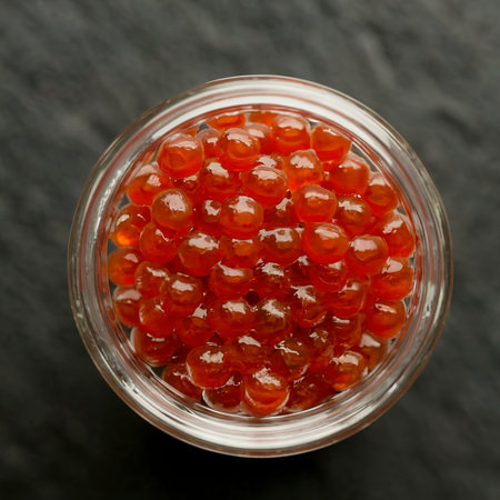 Red caviar in a glass jar on a black background. Close-upの素材