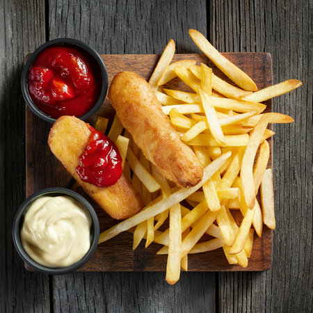 Fish finger and french fries or chips with tomato ketchup and mayonnaise sauce on wooden cutting boardの素材