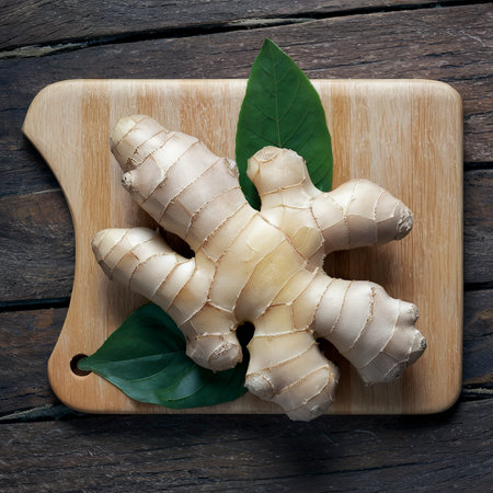 Ginger with leaves on the cutting Board. On wooden backgroundの素材