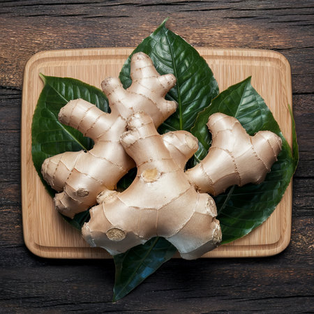 Ginger with leaves on the cutting Board. On wooden backgroundの素材