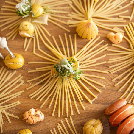 Close-up of decorating Italian pasta. Concept of traditional cuisine and healthy meal. On a wooden backgroundの素材