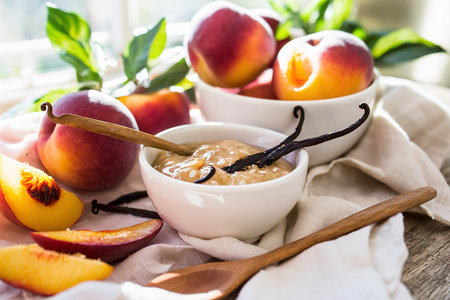 Vanilla peach jam in a bowl with vanilla sticks and fresh peachesの素材