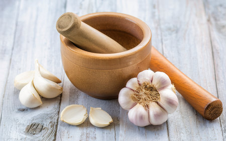 Garlic with mortar and pestle on a wooden background.の素材