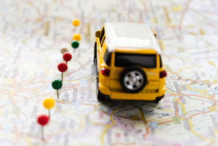 a small yellow toy car with a white roof is placed on a map with several push pins of different colors