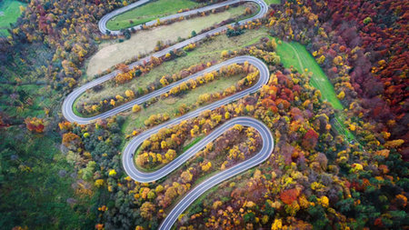 A scenic mountain road curves through vibrant fall foliage and trees.