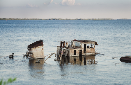 Rusty boat wreck in a blue riverの写真素材