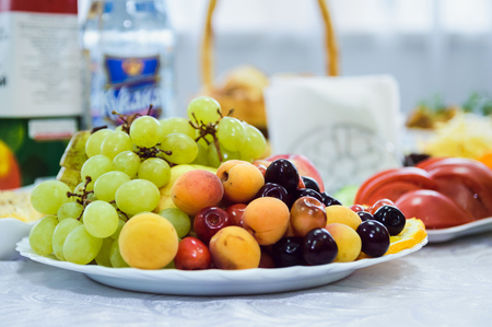 tasty fruit on a plate with cherries, grapes, apricotsの写真素材