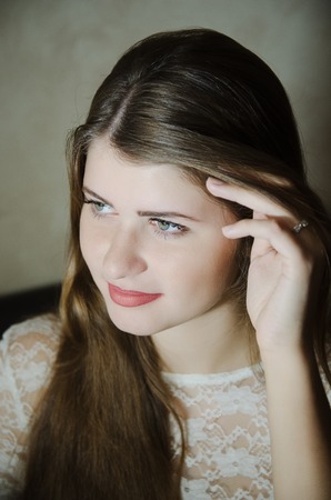 beautiful girl in a white dress with long hair sitting on the couchの写真素材