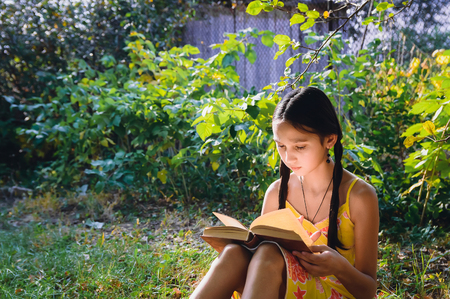 pretty teen girl reading a book in the gardenの写真素材