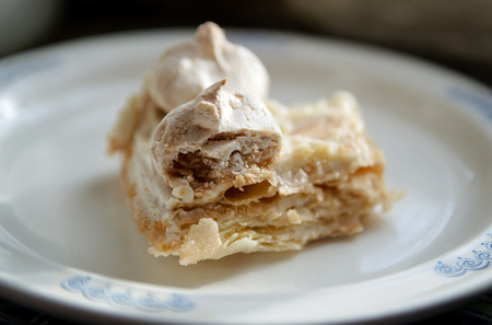 a piece of homemade puff cake with meringue on a white plate closeupの写真素材