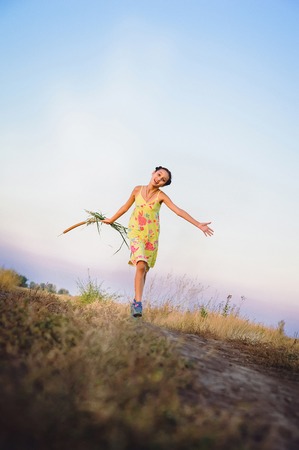 beautiful teen girl in a yellow dress running on the field, summerの写真素材