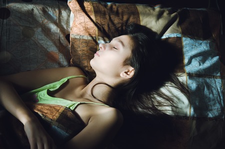 Cute sleeping girl in bedの写真素材