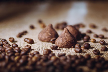 Coffee beans and chocolate candies on sackcloth close up. Coffee and sweets background.の写真素材