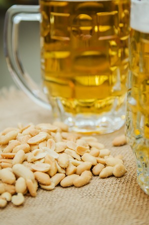 mug with beer and salted peanuts on the tableの写真素材