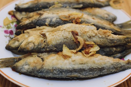 Fried fish Baltic herring lies on a plate on a bamboo napkin.の写真素材