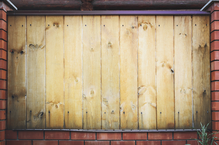 Fragment of a wooden brown modern fence with columns finished with stone , close-up. Modern Style Design wooden Fence Ideas. Front view.の写真素材