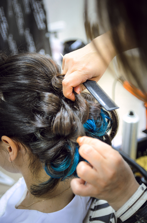Closeup of a professional hairdresser's hands doing a hairstyle in a beauty salon. Model of a brunette with long hair. The concept of fashionable stylish hairstyle, professional work with hair.の写真素材