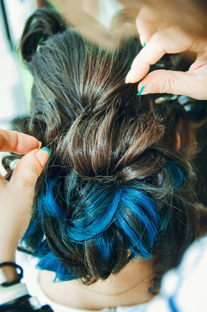 Closeup of a professional hairdresser's hands doing a hairstyle in a beauty salon. Model of a brunette with long hair. The concept of fashionable stylish hairstyle, professional work with hair.の写真素材