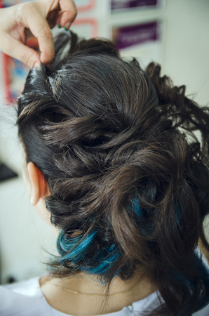 Closeup of a professional hairdresser's hands doing a hairstyle in a beauty salon. Model of a brunette with long hair. The concept of fashionable stylish hairstyle, professional work with hair.の写真素材