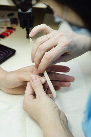 The master does a manicure in the salon, close-up. Vertical photography.の写真素材