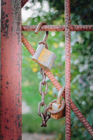 Old rusty open lock hanging on an iron fence.