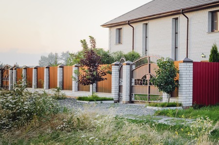 A brown fence made of polyprofile with a canopy in a modern style with brick columns, the design of a country house.の写真素材