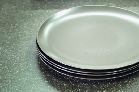 New gray empty plates lie on the table top made of artificial stone. Modern kitchen interior.の写真素材