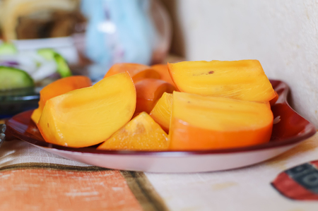 Fresh ripe persimmon, sliced on a plate. Closeup, selective focus.の写真素材