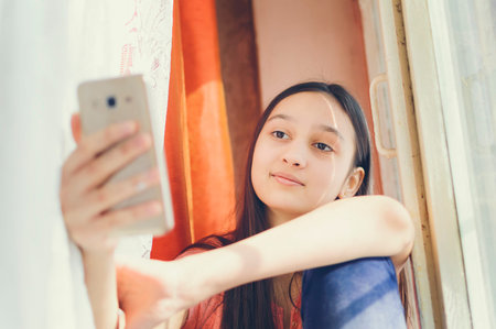 A teenage girl makes selfie on a cell phone.の写真素材