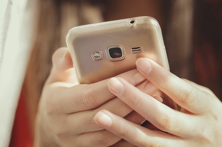 A teenage girl is holding a mobile phone. Closeup, soft focus.の写真素材