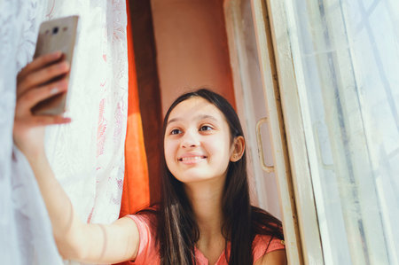 A teenage girl makes selfie on a cell phone.