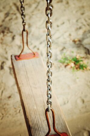 Old wooden swing on an iron chain.の写真素材