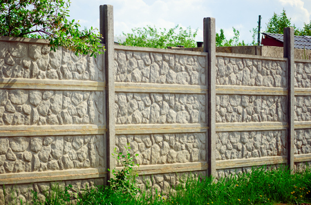 A modern concrete fence near a country house.の写真素材