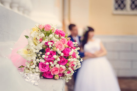 A wedding bouquet close-up against the background of the bride and groom on their wedding day.