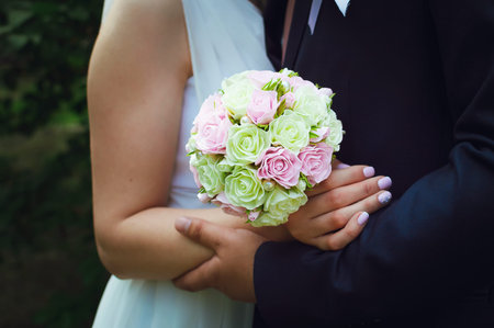 The bridegroom embraces the bride on her wedding day. The bride's bouquet. Close-up.