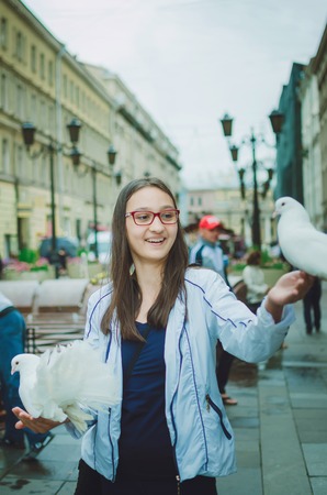 Girl tourist walks through the city of St. Petersburg. Fun with white doves.の写真素材