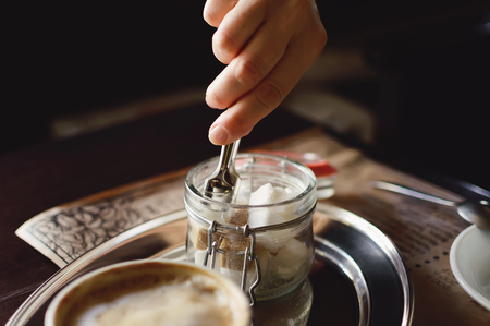 A woman takes sugar in a cafe. Close-up.の写真素材