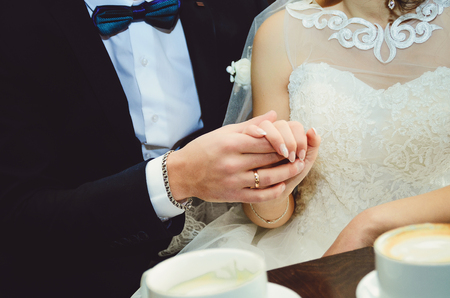 Young married couple holding hands, ceremony wedding day Close-up.の写真素材