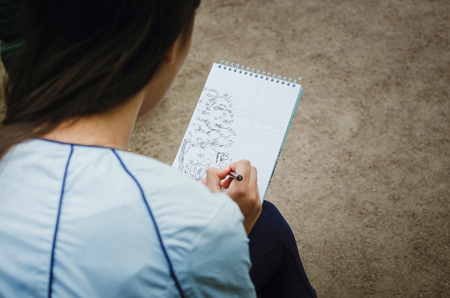 The girl draws in a notebook on the street. Close-up.の写真素材