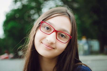 Portrait of a pretty teen girl with glasses. Natural posing on the street.の写真素材