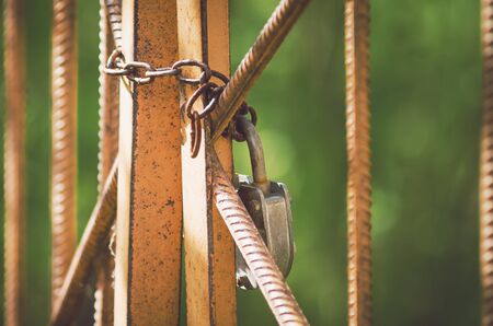 A large closed lock with a chain hangs on an iron gate. The concept of restrictions, prohibitions, closed space, quarantine.の写真素材