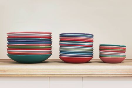 multi-colored plates standing in piles in strict order on the table. 3d render.の写真素材