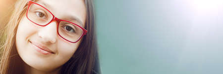 Portrait of a beautiful young girl in glasses. Panoramic banner with place for text, copy space.の写真素材