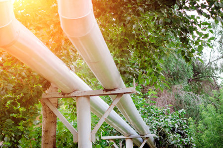 Metal water pipes above the ground in the city, close-up. Soft focus, flare.