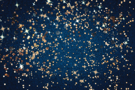 Golden sparkles, lights and decorative baubles on a dark blue background. Christmas background.