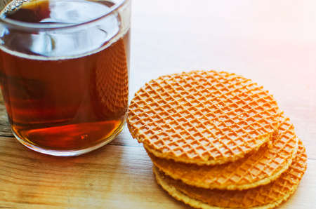 A glass cup of black tea with cookies on a wooden table. Breakfast background.の写真素材