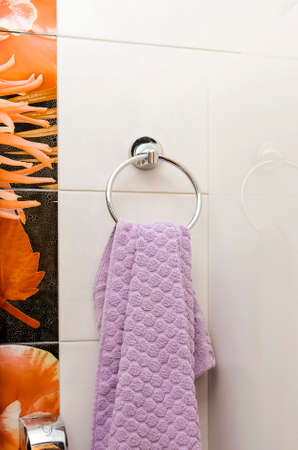 A clean towel hangs on a hanger in the bathroom.の写真素材